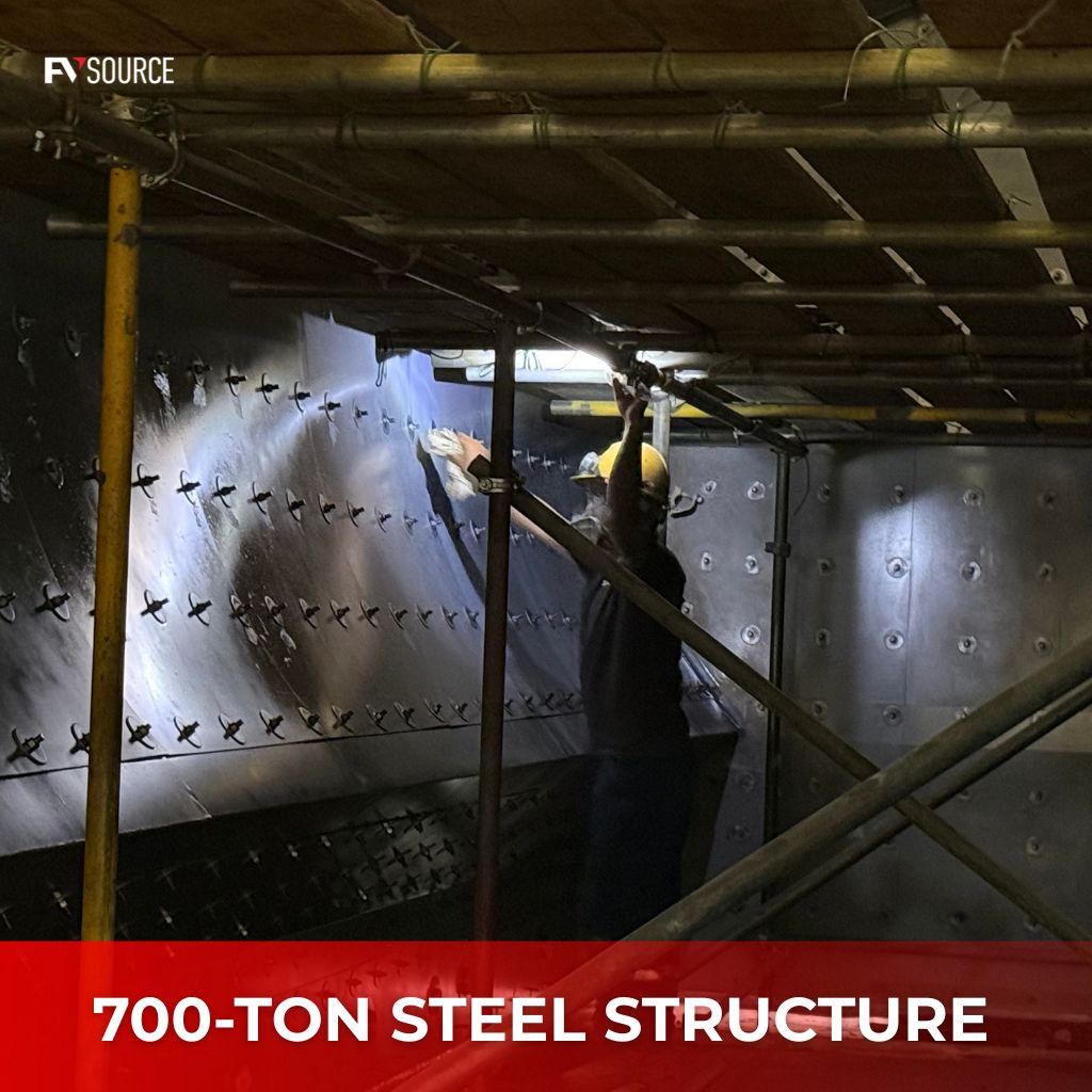 An inspector performing quality control in steel manufacturing Vietnam on a 700-ton industrial steel structure under bright task lighting.